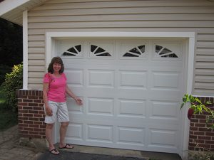Sheila Mulligan poses with her new garage door, professionally installed by Carl’s Door Service in less than two hours.