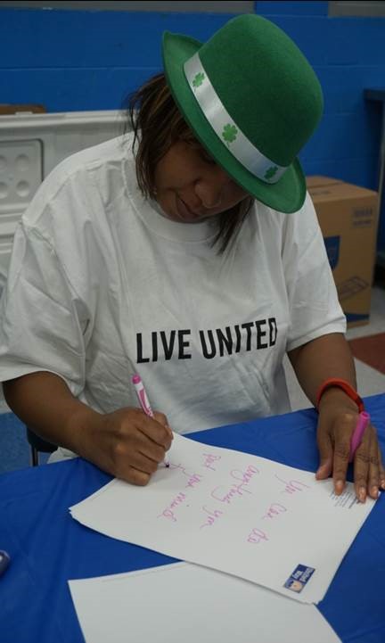 Dominque Mattocks, Dept. of Community Services, writing encouraging messages to the children for their bagged lunches
