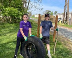 River Sweep volunteers Alonna Kunkel and Brandon Webb, participating with the Conowingo Elementary School’s Environmental Club and Green Team, retrieve a tire from the shoreline at Perryville Community Park during the 2023 cleanup. (Photo Courtesy of Holly Kunkel)